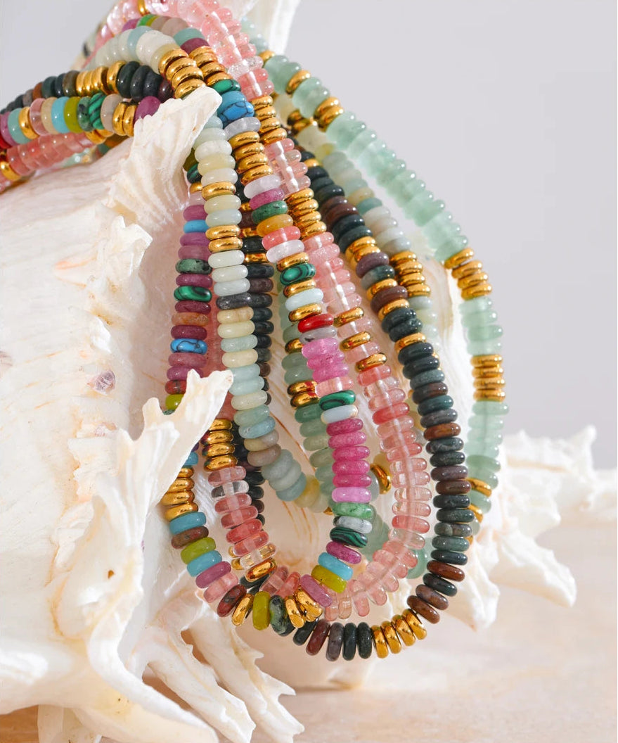 Colourful beaded jewelry set on a shell with a white background