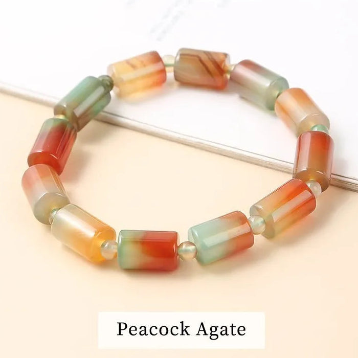 Multicoloured agate bracelet on a light background with 'Peacock Agate' label.