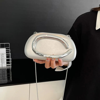 Person holding a silver handbag with a black background