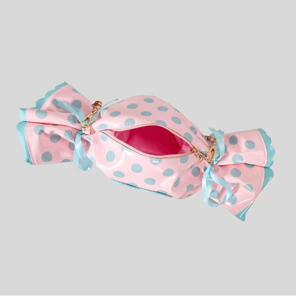 Pink polka dot candy bag with blue ribbons on a grey background