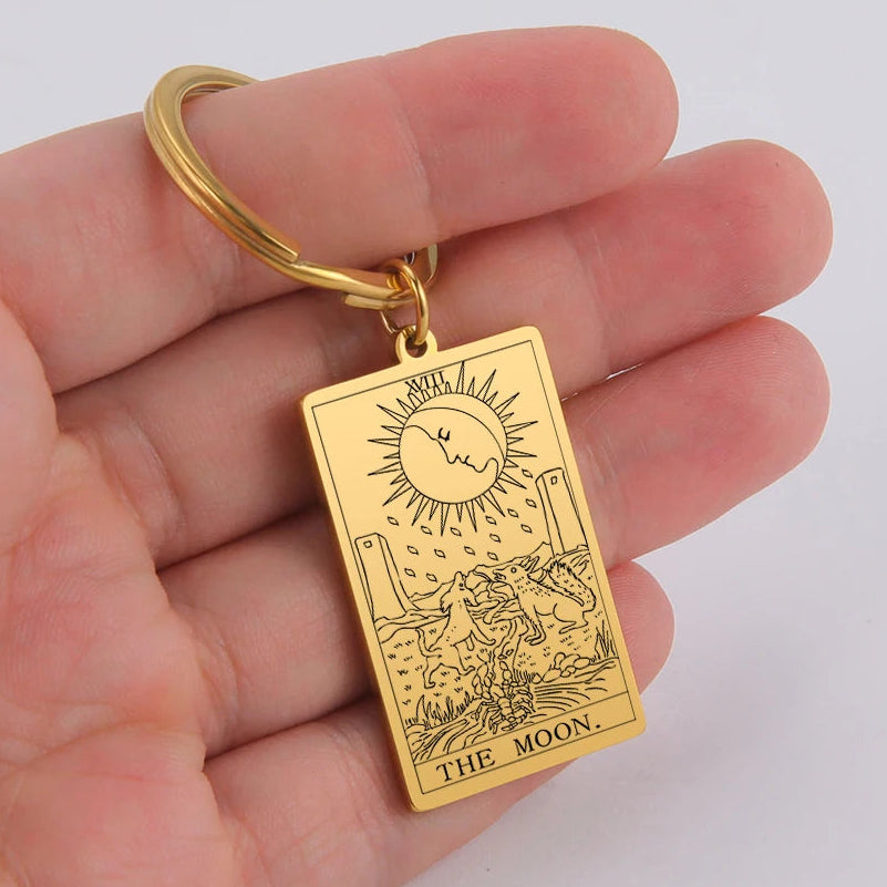 Gold keychain with 'The Moon' tarot card design held in a hand against a white background