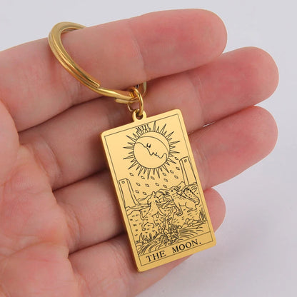 Gold keychain with 'The Moon' tarot card design held in a hand against a white background