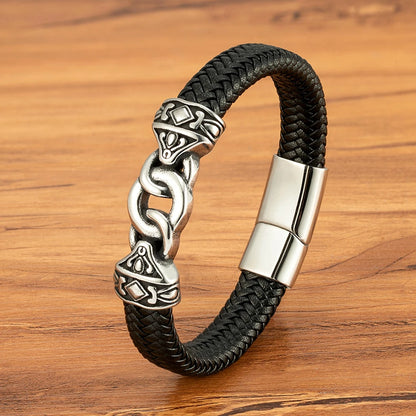 Black braided leather bracelet with silver Celtic knot design on a wooden surface
