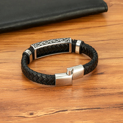 Black leather bracelet with silver clasp on a wooden surface