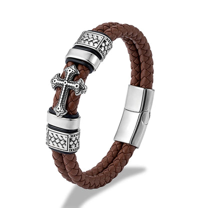A brown braided leather bracelet with silver-tone metal accents, including a decorative cross charm, textured spacer beads, and a magnetic clasp, shown on a white background.