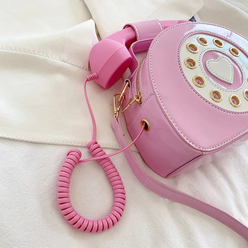 Pink phone-shaped handbag with coiled handle on a light background