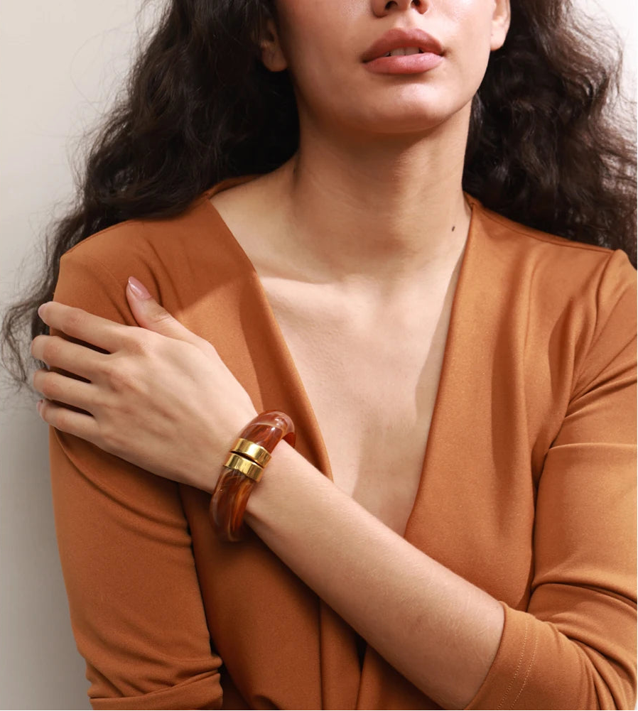 Woman wearing a rust-coloured top with a plain background