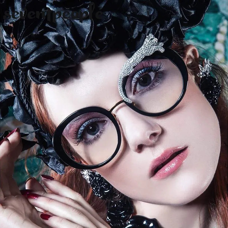 Woman wearing large black glasses and decorative headpiece with floral elements.