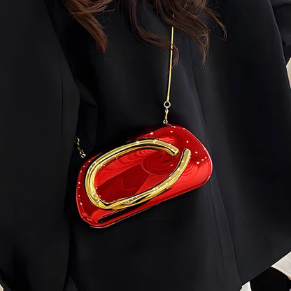 Red and gold handbag held by a person wearing a black coat.
