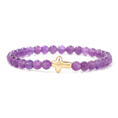 Purple beaded bracelet with a gold cross charm on a white background