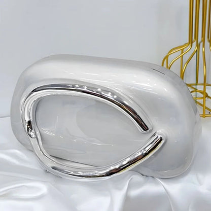 Silver clutch bag on a white surface.