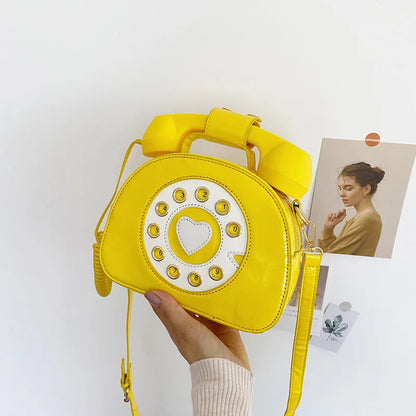 Yellow phone-shaped bag held by a hand with a light background
