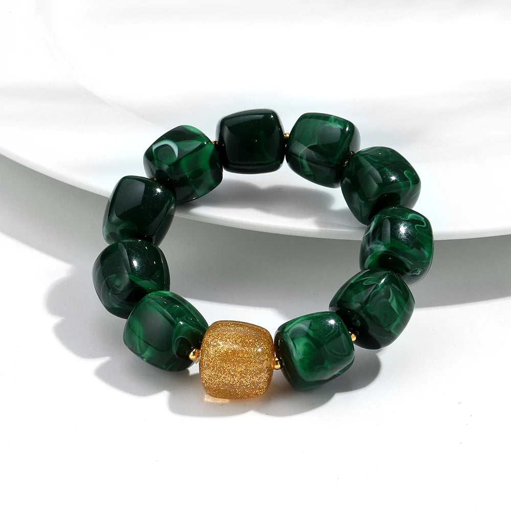 Green beaded bracelet with a gold accent on a white surface