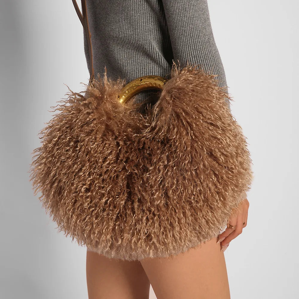 Brown fluffy handbag with a gold handle held by a person wearing a grey sweater.