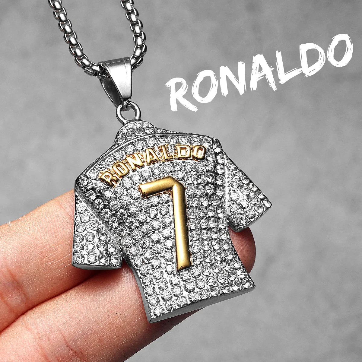 Pendant shaped like a sports jersey with 'RONALDO' and number '7', held by a hand against a grey background.