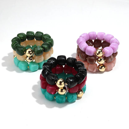 Set of colourful beaded bracelets with gold accents on a white background