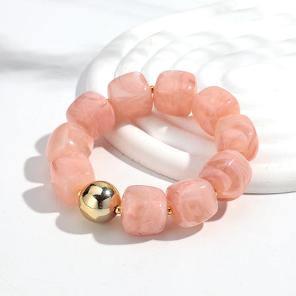 Pink beaded bracelet with a gold accent on a white background