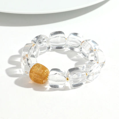 Clear bracelet with a gold bead on a white background