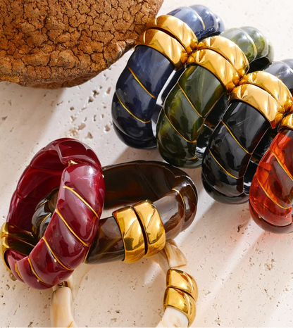 Colourful acrylic bracelets with gold accents on a textured surface