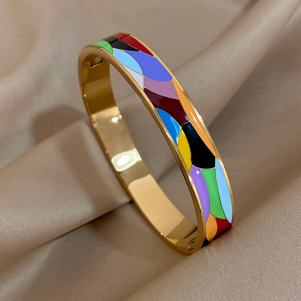 Gold bangle with colourful inlay on a beige fabric background