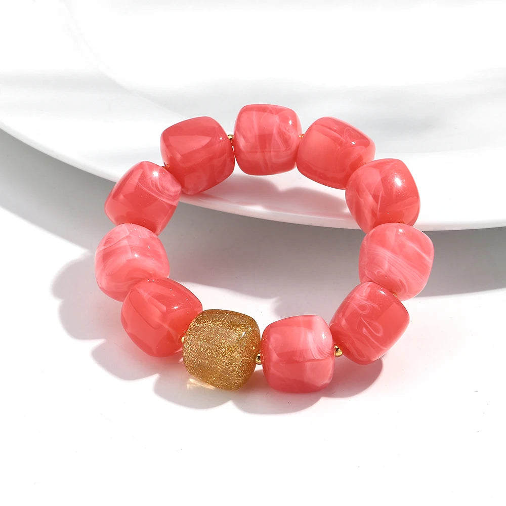 Pink beaded bracelet with a gold accent on a white background