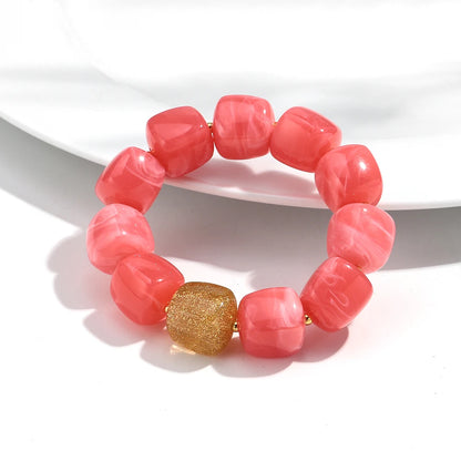 Pink beaded bracelet with a gold accent on a white background