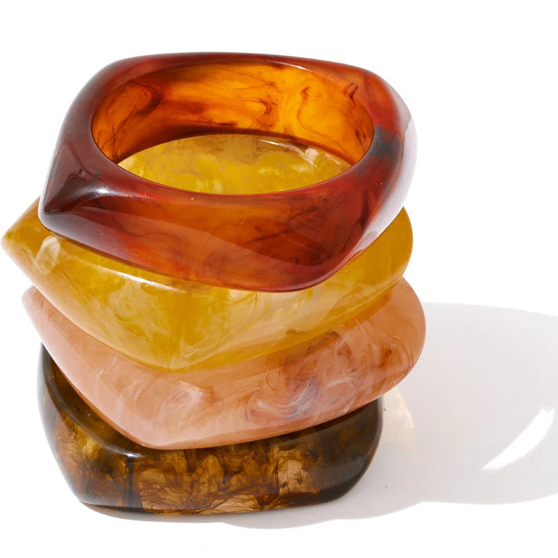 Stack of multicoloured resin bracelets on a white background