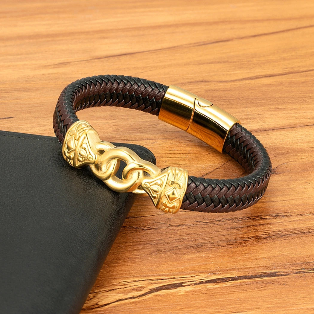 Brown braided leather bracelet with gold clasp on a wooden surface