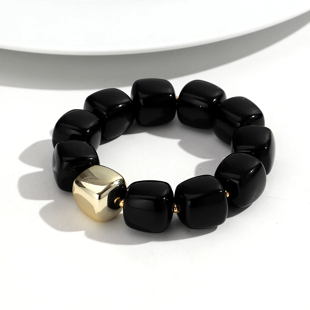 Black beaded bracelet with a gold accent on a white surface