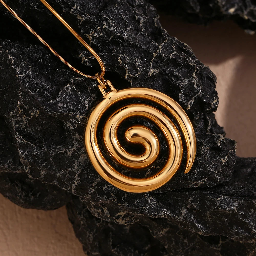 Gold spiral pendant on a dark stone surface