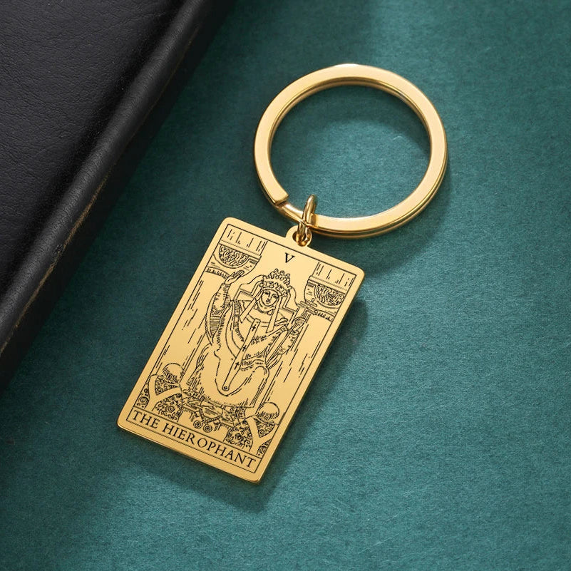 Gold keychain with tarot card design on a teal surface