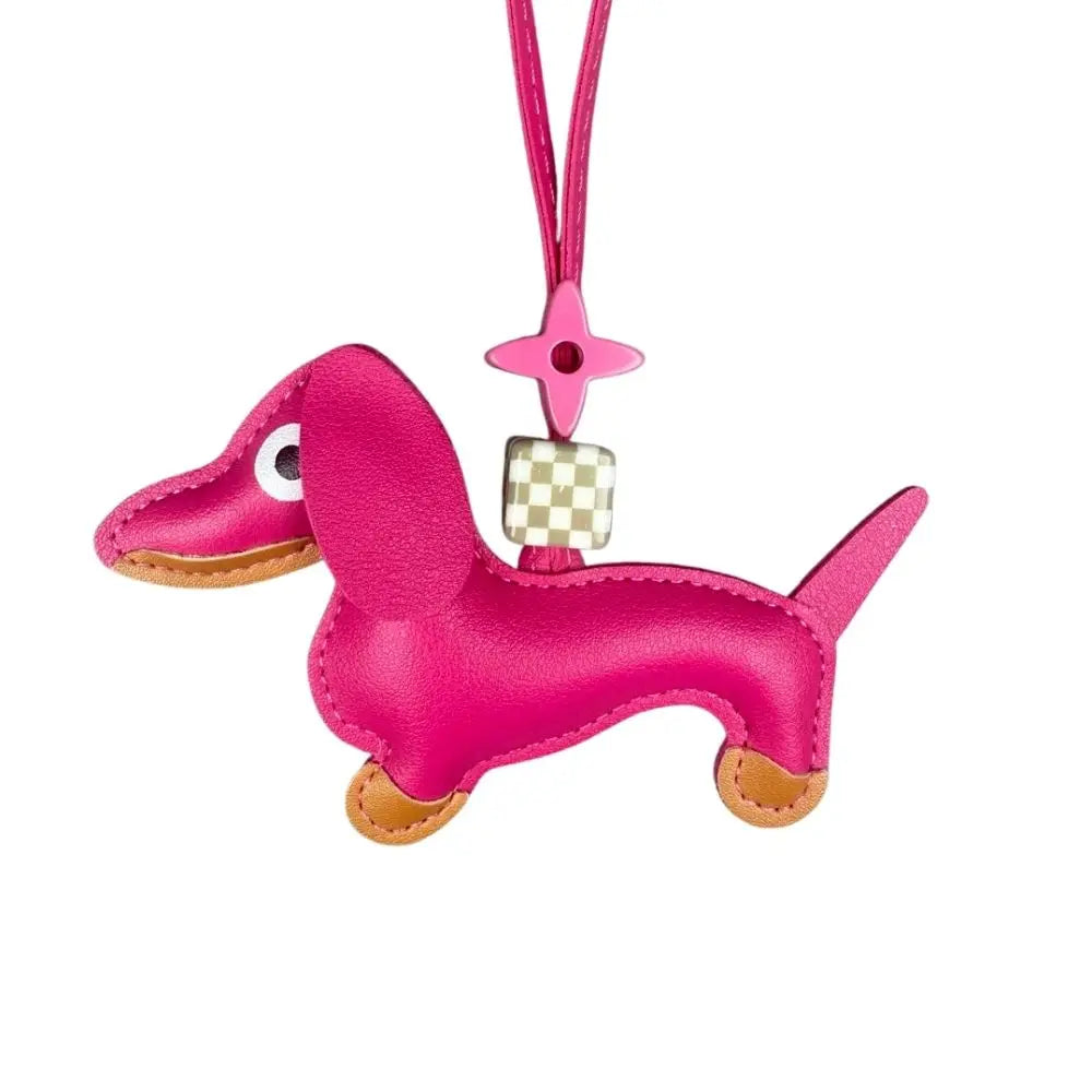 Pink dachshund-shaped keychain with a checkered charm on a white background