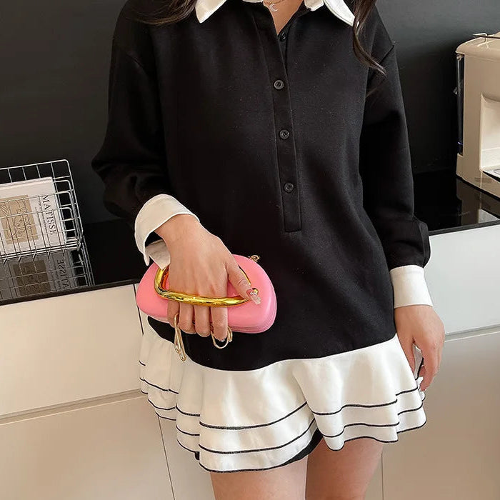 Person wearing a black shirt with white collar and skirt, holding a pink clutch.