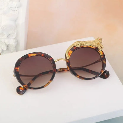 Sunglasses with tortoiseshell frame and gold accents on a white surface