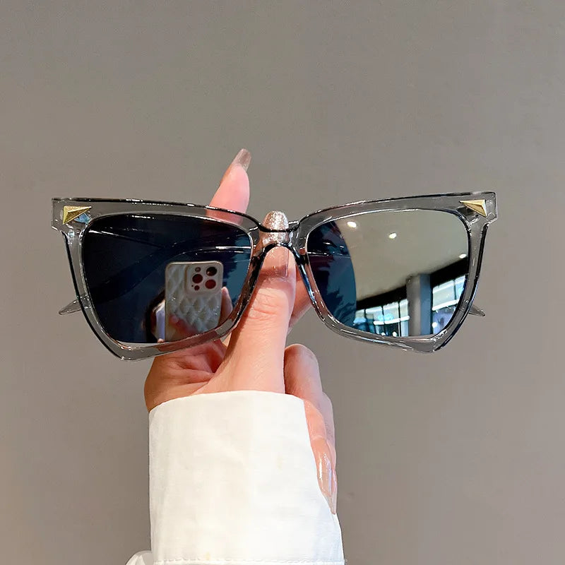Person holding a pair of sunglasses  against a neutral background