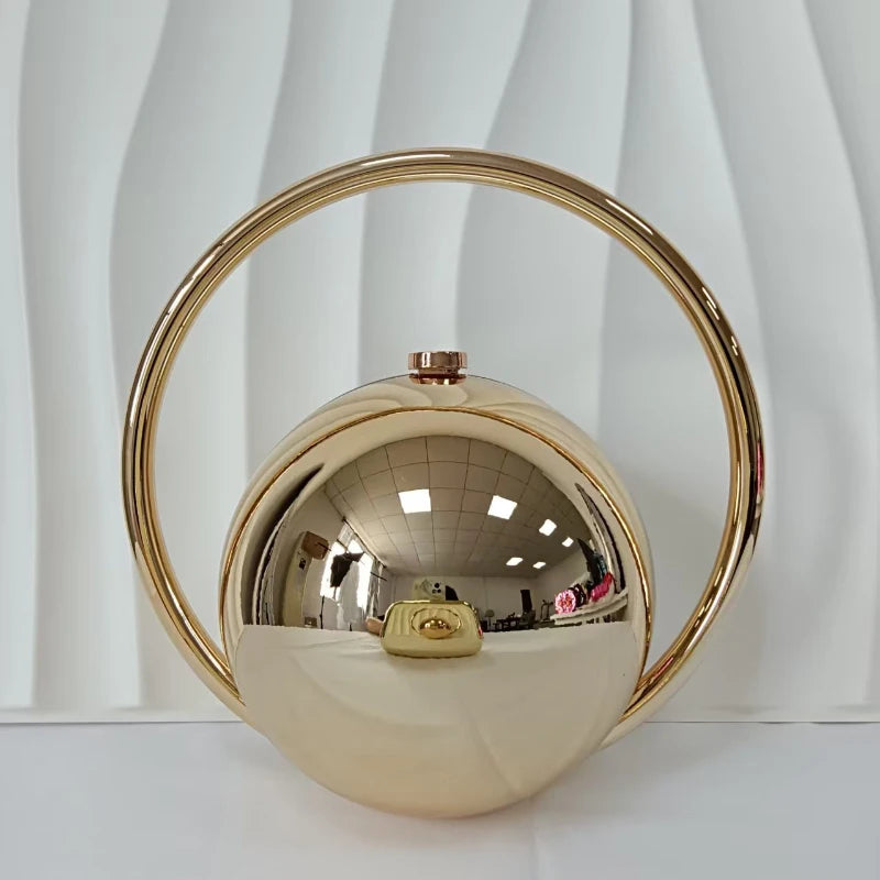 Gold spherical handbag with a circular handle on a white background