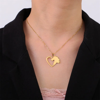 Gold necklace with a heart-shaped pendant featuring a horse design on a person wearing a black jacket.
