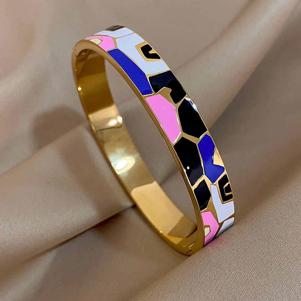 Gold bracelet with colourful geometric pattern on a beige fabric background