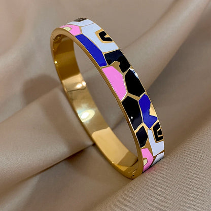 Gold bracelet with colourful geometric pattern on a beige fabric background