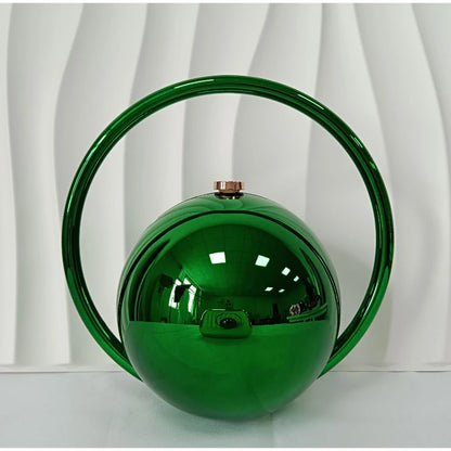 Green spherical handbag with a handle against a white curtain background