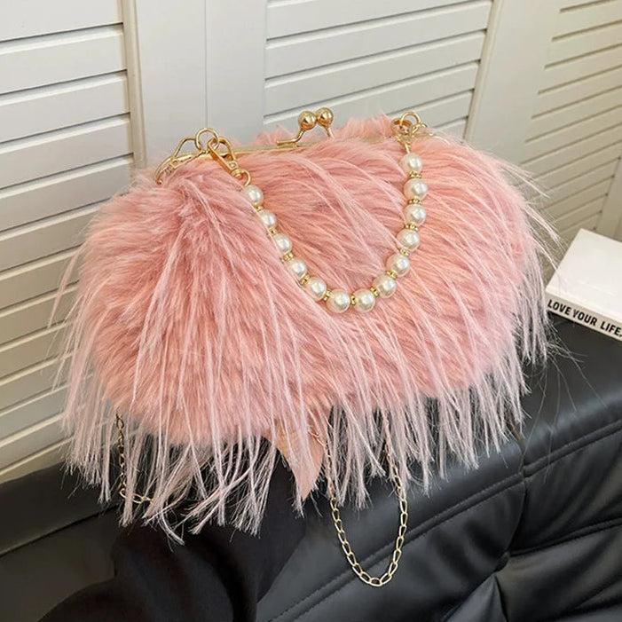 Pink feathered handbag with pearl chain on a black surface