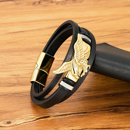Black leather bracelet with gold eagle clasp on a wooden surface