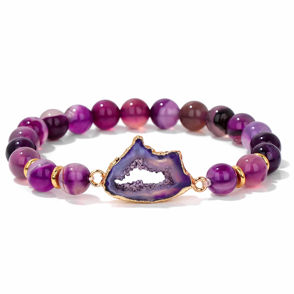 Purple beaded bracelet with a gold and purple geode charm on a white background