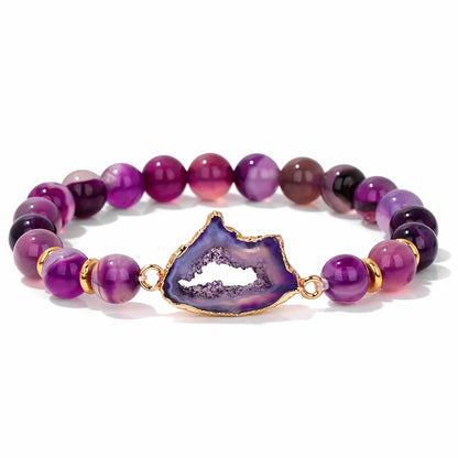 Purple beaded bracelet with a gold and purple geode charm on a white background