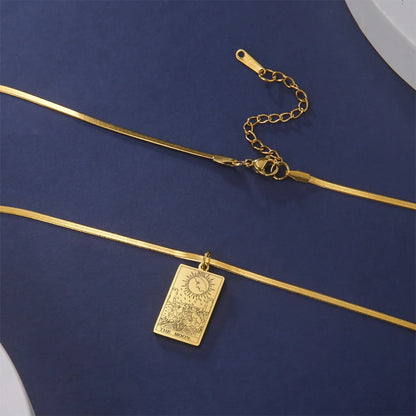 Gold necklace with a rectangular pendant on a blue fabric background