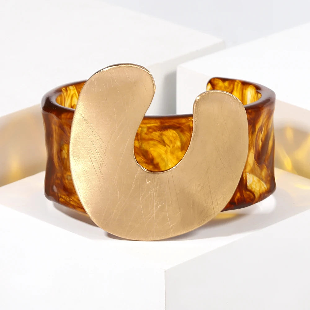 Brass bracelet with tortoiseshell-like band on a white background