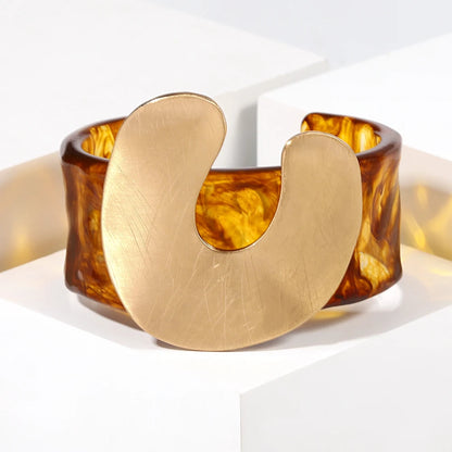 Brass bracelet with tortoiseshell-like band on a white background