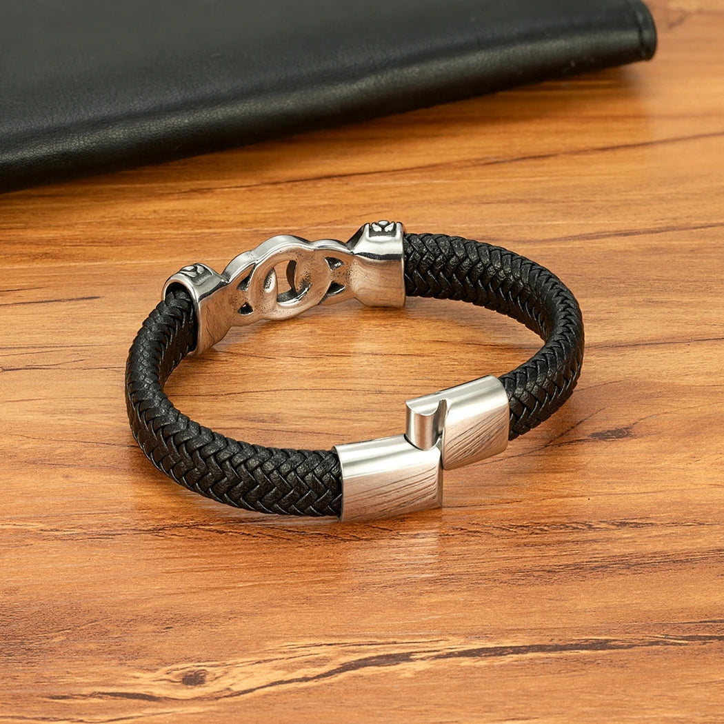Black braided leather bracelet with silver clasp on a wooden surface