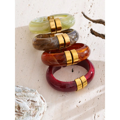 Set of colourful bangles with gold accents on a textured surface