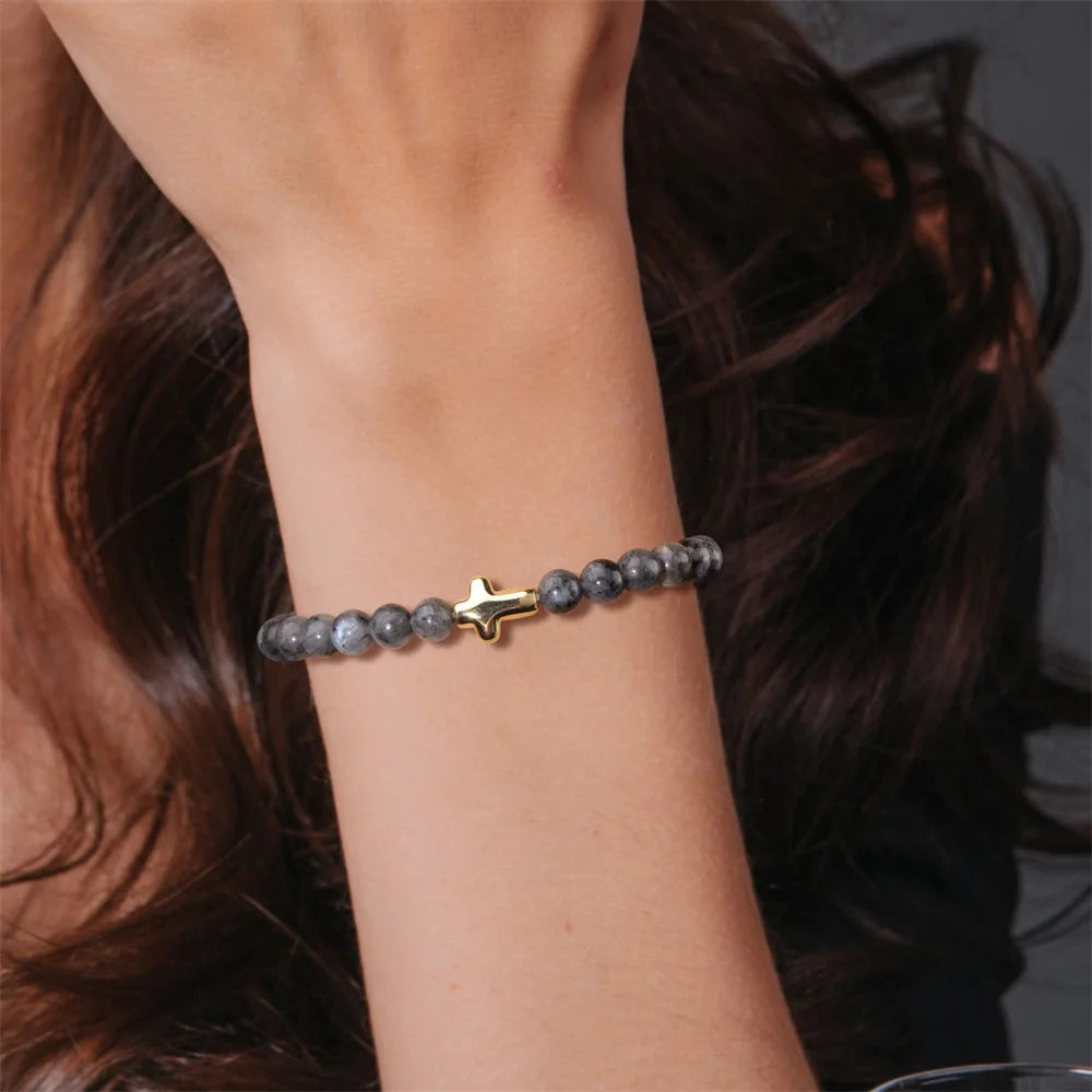 Bracelet with a cross charm on a wrist against a blurred background